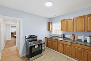 A kitchen with wooden cabinets, stainless steel appliances, and a window. - Niagara Adventure Basecamp Walk To The Falls 2 Bedroom Duplex (Niagara Falls)