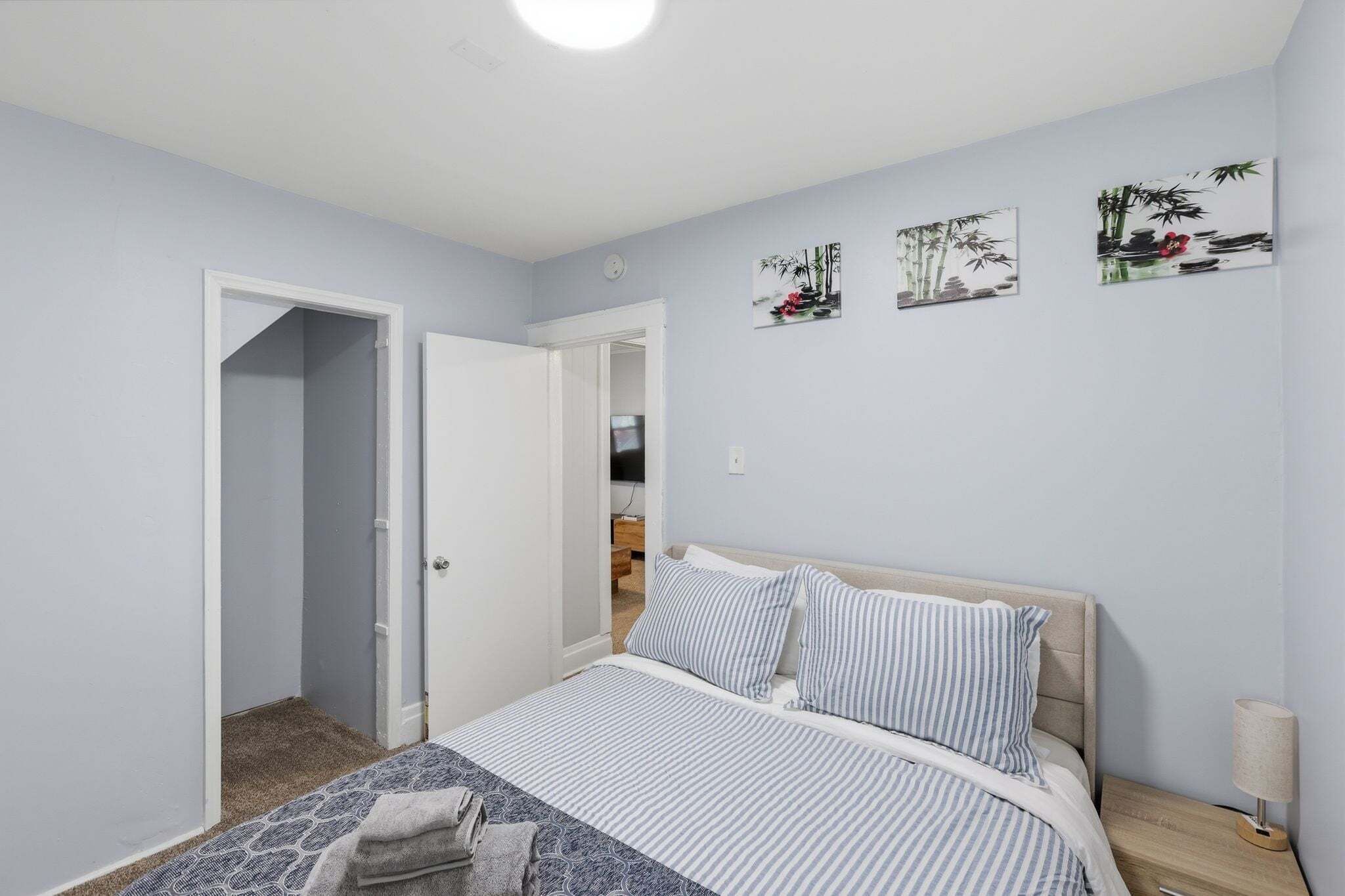 Une chambre à coucher comprenant un lit, une table de chevet, une lampe et une porte donnant sur une autre pièce.