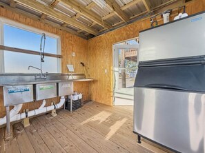 Ett kompakt kök med ett kylskåp i rostfritt stål, träväggar, ett fönster och en diskho med vattenledningar.