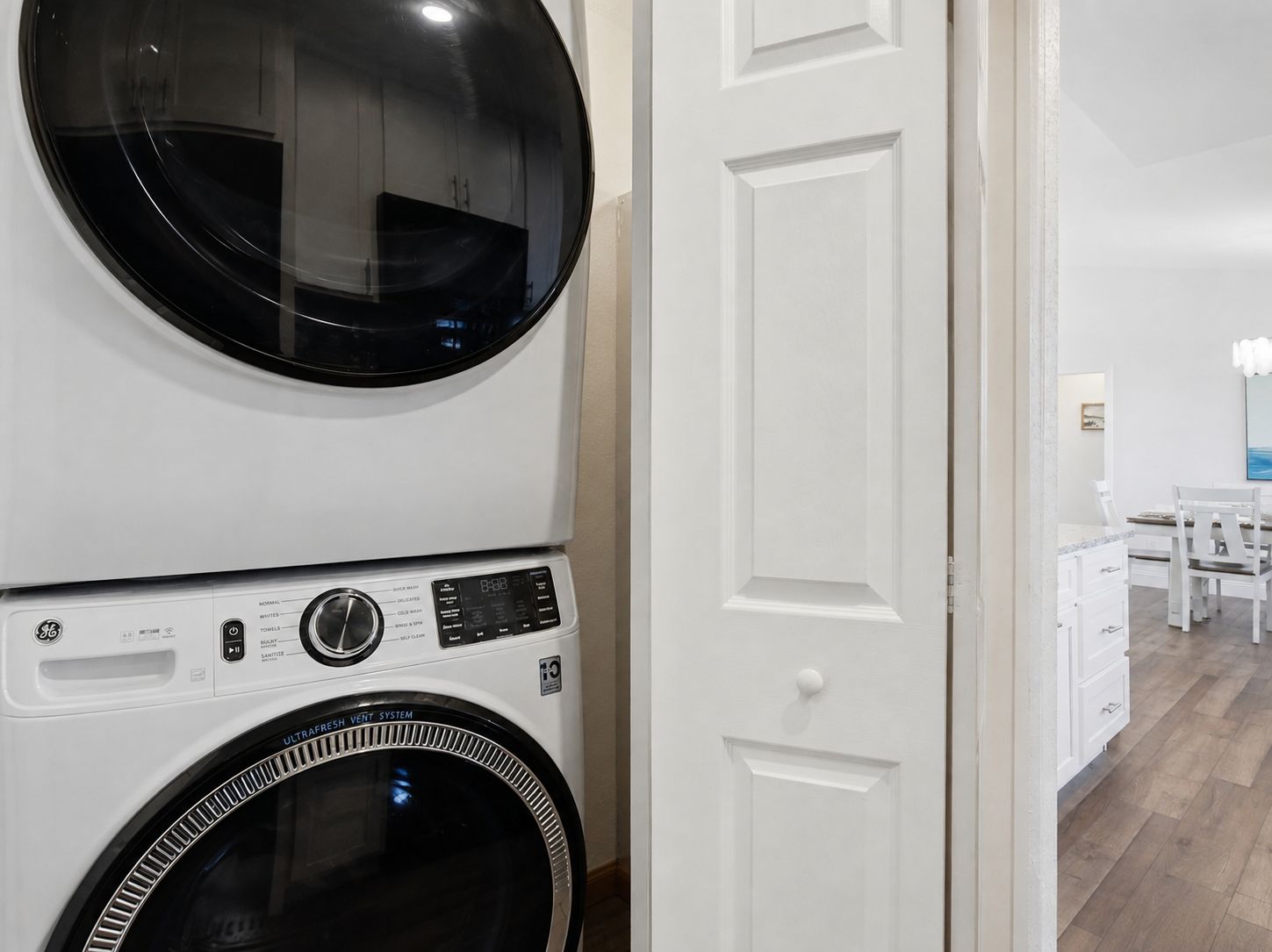 A laundry room with two stacked washing machines and a white door.