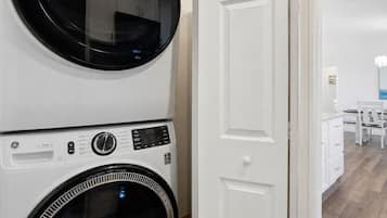 A laundry room with two stacked washing machines and a white door.