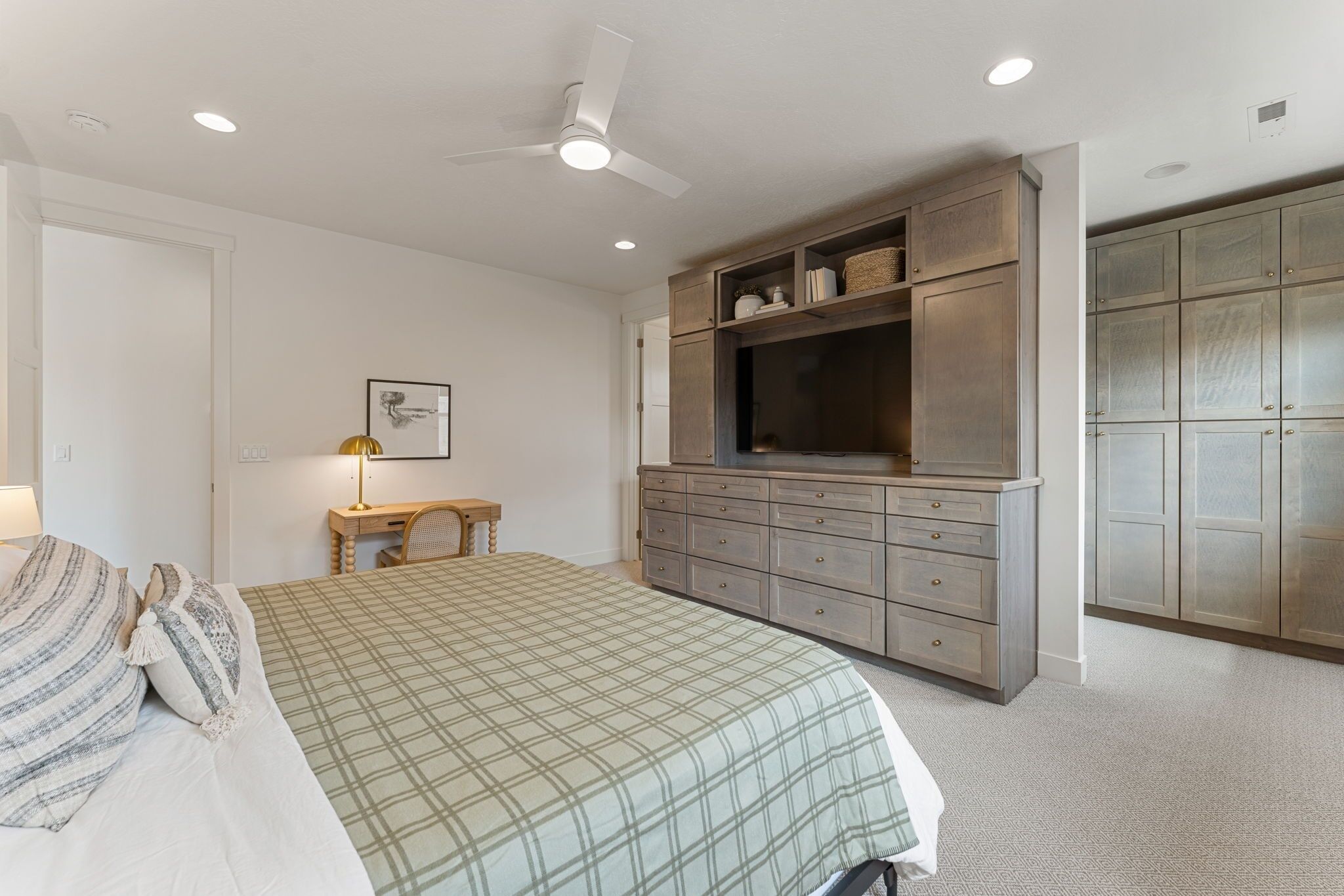 Une chambre à coucher comprenant un lit, un bureau, une armoire et un ventilateur de plafond.