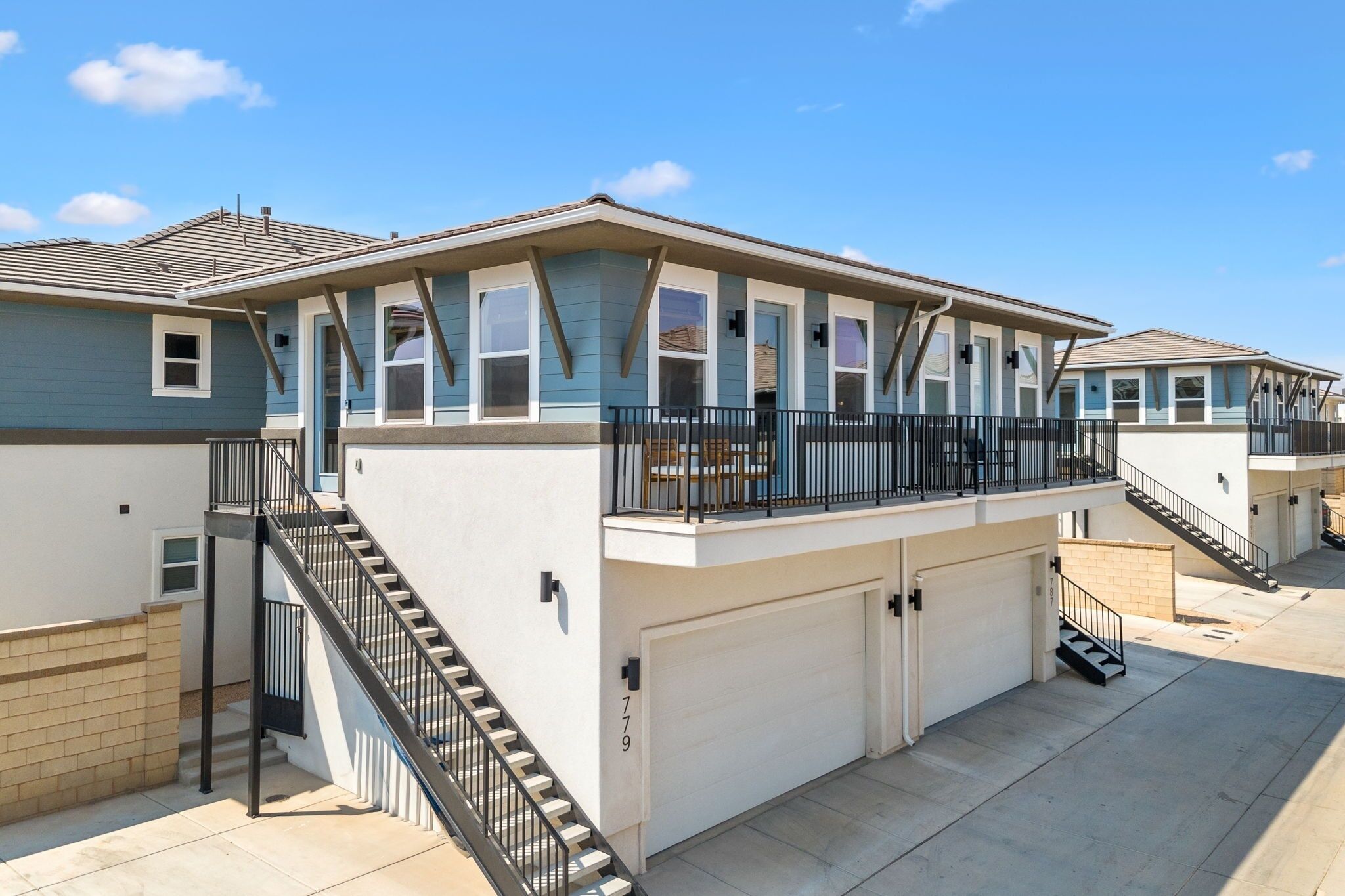 A two-story residential building with a balcony, a garage, and a stairway.