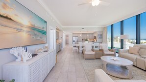 A spacious living area with a large TV, comfortable seating, a ceiling fan, and a view of the ocean. - Phoenix Gulf Shores Ii 405 4 Bedroom Condo (Gulf Shores)