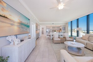 A spacious living area with a large TV, comfortable seating, a ceiling fan, and a view of the ocean. - Phoenix Gulf Shores Ii 405 4 Bedroom Condo (Gulf Shores)