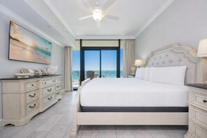 A hotel room with a large bed, a dresser, a painting, and a view of the ocean. - Phoenix Gulf Shores Ii 405 4 Bedroom Condo (Gulf Shores)