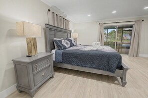 Un dormitorio con cama, mesita de noche y vistas a través de un ventanal corredera.
