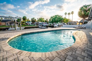 A swimming pool with a curved edge, surrounded by a paved deck. - Harbor Island - 4900 Shoreview Ct 3 Bedroom Home (Port Richey)