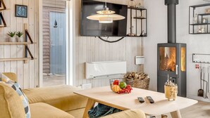 Ein gemütliches Wohnzimmer mit Fernseher, Kamin, Holzwänden und einem Essbereich mit Obstschale.