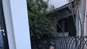 Uma pequena área de estar ao ar livre com mesa de vidro e duas cadeiras.
