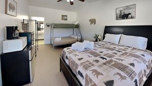 Un dormitorio con cama, escritorio, silla, ventilador de techo y literas.