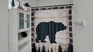 Un baño con un mueble blanco, un inodoro y una cortina de ducha con un diseño de oso.