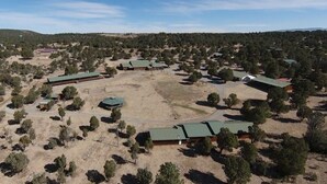 Vista aérea de una zona residencial con varias casas, rodeada de árboles y terreno abierto.