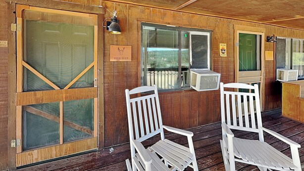 A wooden deck with two white chairs, a chalkboard with writing, and a sign reading 'BUCK DEER.' - Buck Deer Cabinette: Studio + Mountain Views! (Alto)