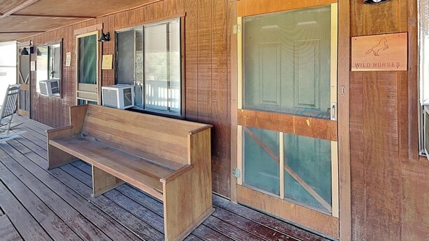 A wooden exterior with a bench, a door labeled 'WILD HORSES,' and a window with a view. - Wild Horses Cabinette: Studio + Mountain Views! (Alto)