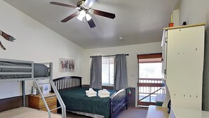 A bedroom with bunk beds, a single bed, a ceiling fan, a window with curtains, and a door leading outside. - Wild Horses Cabinette: Studio + Mountain Views! (Alto)