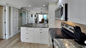 Una cocina moderna con armarios blancos, encimera de granito, horno integrado y microondas.