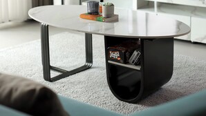 Una sala de estar moderna con una mesa redonda, una planta en maceta y un televisor de pantalla plana sobre un mueble blanco.