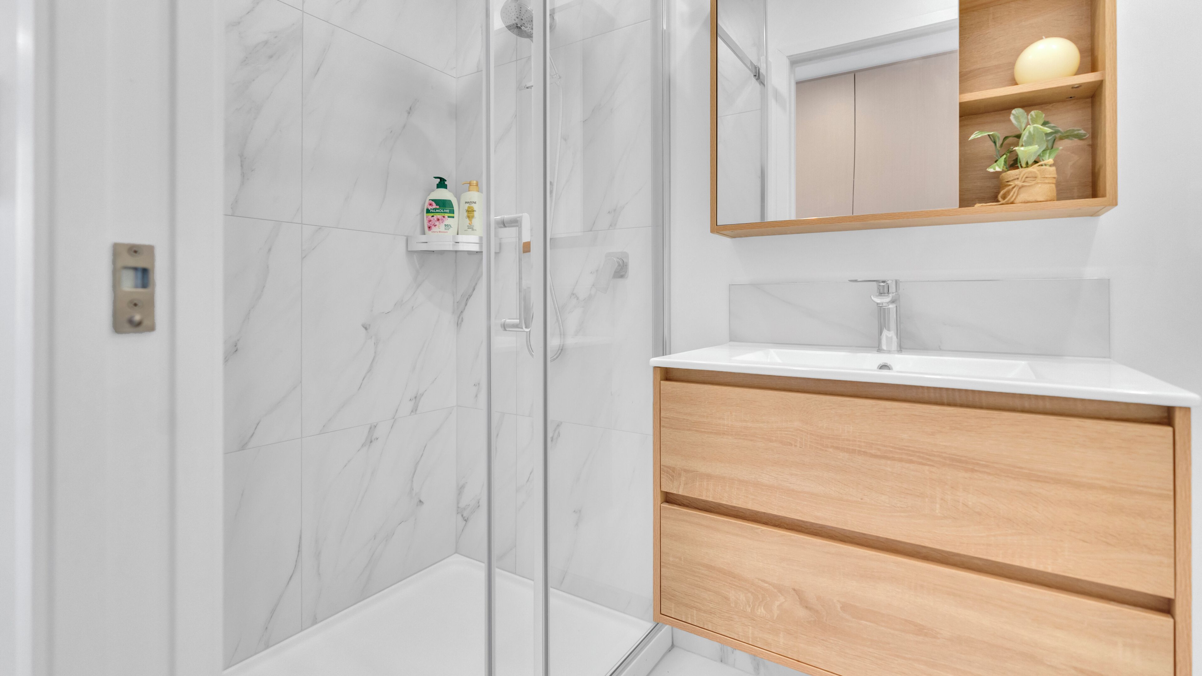 Une salle de bain moderne avec une douche à parois de verre, un lavabo blanc et des meubles en bois.