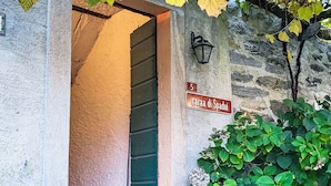 Une entrée d’immeuble avec une porte verte, un mur en pierre et une enseigne indiquant « Casa di Spadui ».