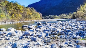 Une rivière parsemée de gros rochers, avec une montagne en arrière-plan.