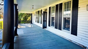 A covered porch with a railing, a series of windows with shutters, and a ceiling with a light fixture. - Modern 1 BR Near York - Sleeps 3 - Renovated (Hallam)