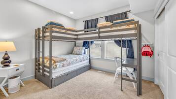 A bunk bed room with a desk, chair, lamp, and a red backpack.