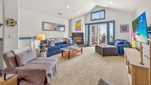 A living room with a fireplace, a sofa, a coffee table, and a TV. - Eazy Breezy: Ocean Views, Dog-Friendly Rockaway Beach Townhome for 8 (Rockaway Beach)