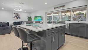 Una cucina moderna con un'isola grande, mobili grigi e vista sulla spiaggia.