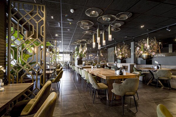 A restaurant interior with high ceilings, pendant lighting, and a variety of seating arrangements including tables and chairs.