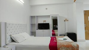 Une chambre d’hôtel avec un lit, une télévision, une armoire et un bureau.