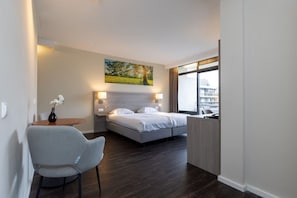 A hotel room with a bed, bedside lamps, a chair, a table with a vase, and a window with a view. - Table Tennis, Game Room and Garden Walks with Convenient Free Parking (Winterswijk)