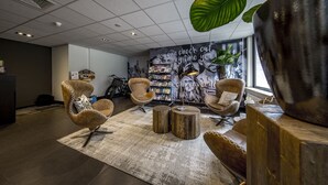 A modern lounge area with leather chairs, wooden stools, and a large mural. - Active Dutch Getaway with Cycling Routes, Pool Access and Free Parking (Winterswijk)