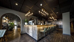 Un espace bar moderne doté d’un comptoir central, de tabourets de bar et de luminaires suspendus.
