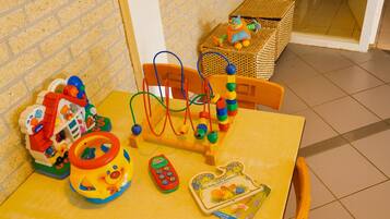 A yellow table with a toy abacus, a toy house, a toy car, and a book.