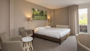 A hotel room with a bed, two chairs, a small table, and a painting on the wall. - Relax and Unwind with Free Parking, On-Site Dining, and Stunning Lake View (Velsen-Zuid)