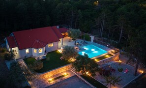 Ein Haus mit Schwimmbad, umgeben von gepflegtem Rasen und Bäumen.