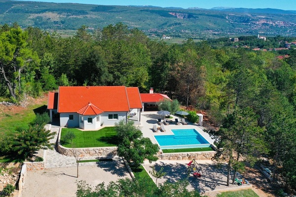 An aerial view shows the 250 sqm villa, the expansive pool, and a grassy plot with a swing and slide for children.
