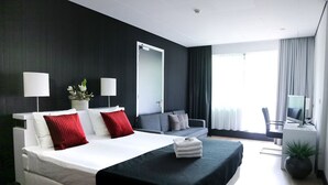 Ein modernes Hotelzimmer mit einem großen Bett, einem Schreibtisch, einem Fernseher und einer Zimmerpflanze.