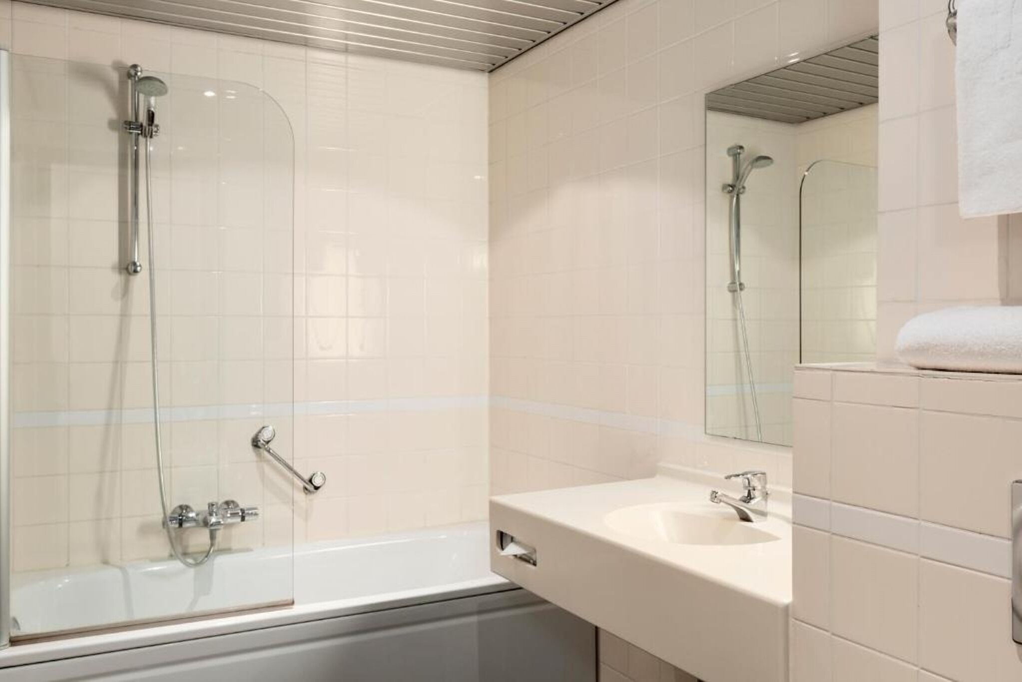 A bathroom with a glass-enclosed shower, a sink, and a mirror.