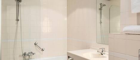 A bathroom with a glass-enclosed shower, a sink, and a mirror.