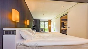 Une chambre d’hôtel moderne, dotée d’un grand lit, d’un bureau et offrant une vue sur l’extérieur.
