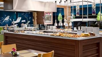 A buffet setup with a variety of food items, a coffee machine, and hanging pendant lights.