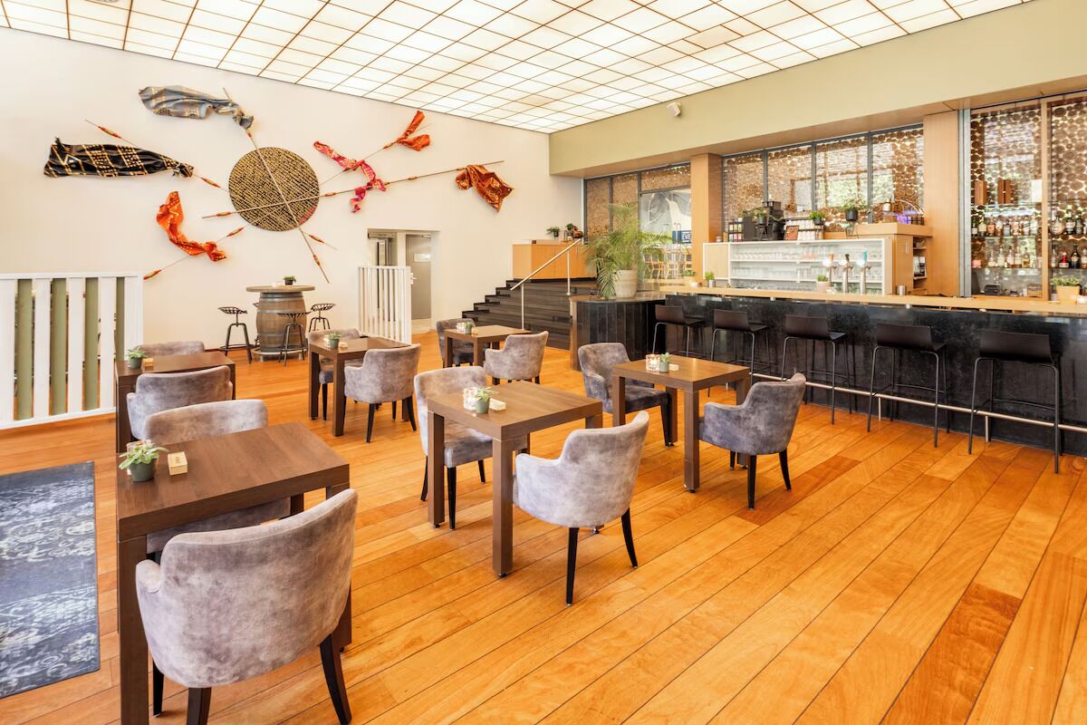 Un espace bar moderne avec un plancher en bois, des tabourets de bar et un comptoir offrant une vue sur la ville.