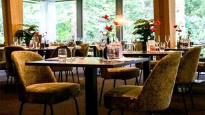 A restaurant with tables set for dining, chairs, and a chandelier.