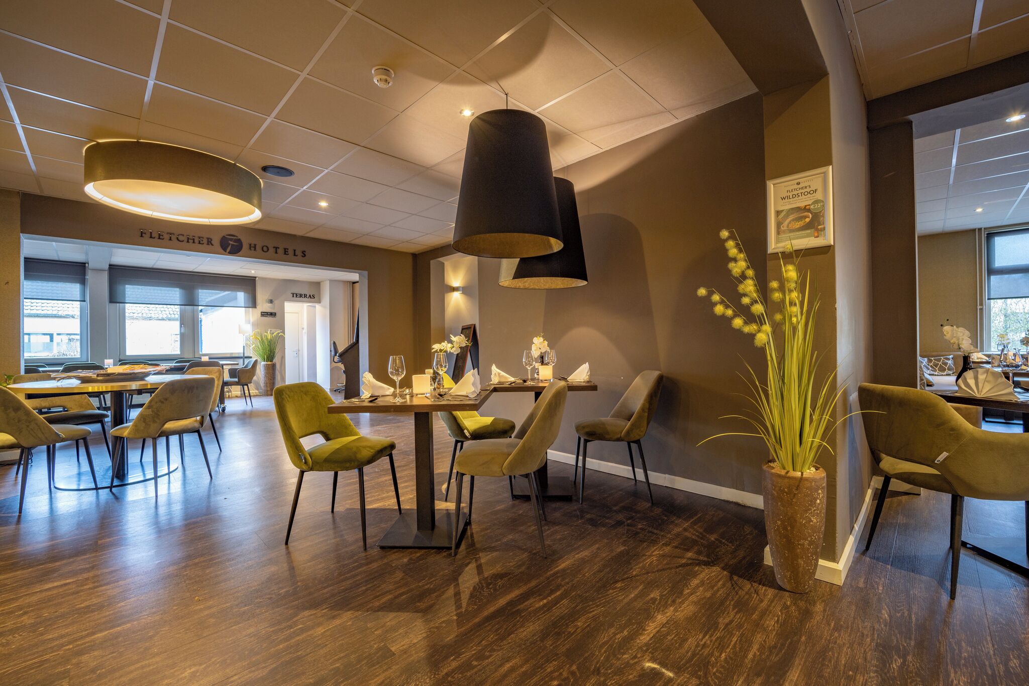 Een hotel lobby met een eetgedeelte, modern meubilair en een grote potplant.