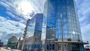 Ein modernes Hotel mit Glasfassade, einem markanten Eingang und blauem Himmel.