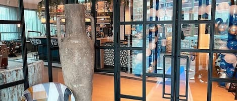 Una habitación con un ventanal grande, una silla y una estructura decorativa de piedra.