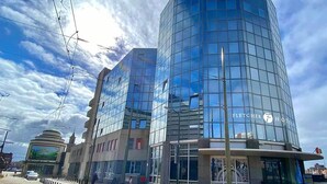 Ein modernes Hotel mit Glasfassade, einem markanten Eingang und blauem Himmel.