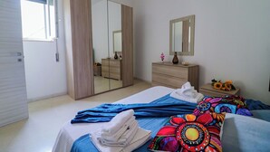 Une chambre à coucher comprenant un lit, une commode, un miroir et une armoire.
